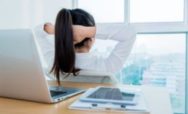 a woman at a desk, head in hands, reflecting on her journey in an emotional resilience course