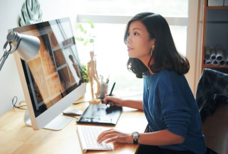 A woman at a desk, working on a computer and keyboard to create a WordPress website