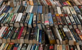 A table stacked with numerous books, primarily fiction writing, forming a substantial pile