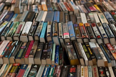 A table stacked with numerous books, primarily fiction writing, forming a substantial pile