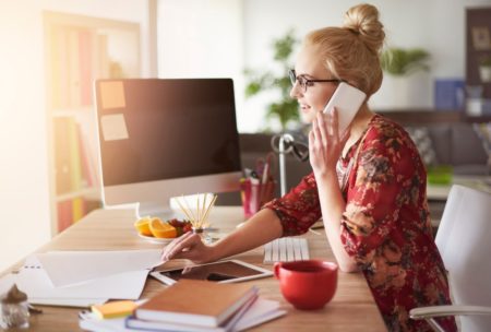 a woman seated at a desk, engaged in a phone conversation, embodying the essence of Fiverr secrets in her work
