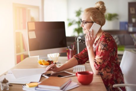 a woman seated at a desk, engaged in a phone conversation, embodying the essence of Fiverr secrets in her work
