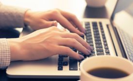 A person typing on a laptop computer, working on freelance remote jobs