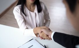 a woman and man shaking hands at a desk, symbolizing how to find your perfect job