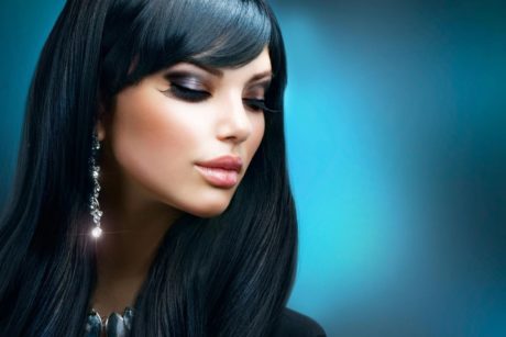 Elegant woman with long black hair and earrings, showcasing her stylish hair and make up