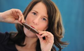 A woman learning how to play harmonica.