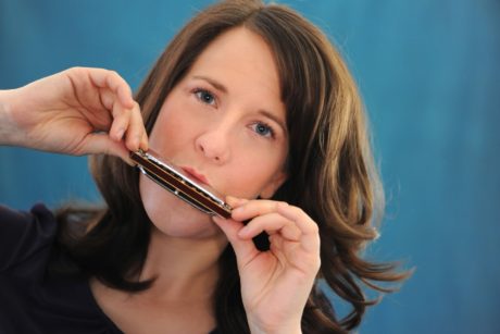 A woman learning how to play harmonica.