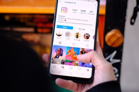 A hand holding a cellphone is scrolling through Instagram after taking an Instagram marketing course