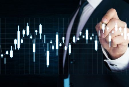 a man in a suit points at a data chart during a stock investing course presentation