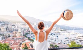 woman raising arms looking at view of foreign city