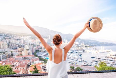 woman raising arms looking at view of foreign city