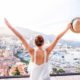 woman raising arms looking at view of foreign city