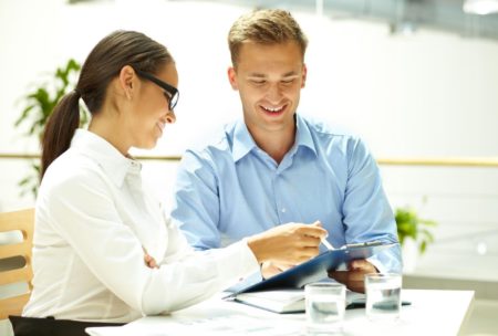a man and woman seated with a tablet, showcasing an abundance mindset