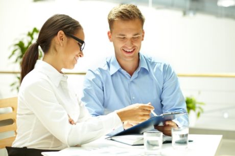 a man and woman seated with a tablet, showcasing an abundance mindset