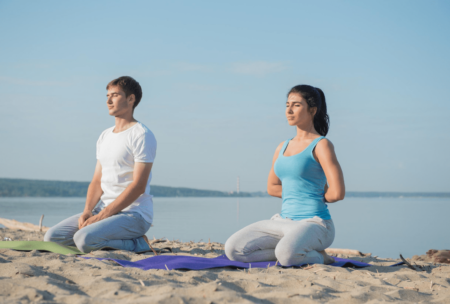 a serene beach scene featuring a couple engaged in yoga, promoting mindfulness meditation course