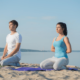 a serene beach scene featuring a couple engaged in yoga, promoting mindfulness meditation course