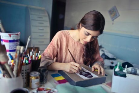 A woman focused on her artwork, painting in her studio while learning the art of painting for beginners