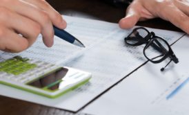 a businessman’s hands engaged with a calculator and pen on financial documents, representing a personal finance course setting