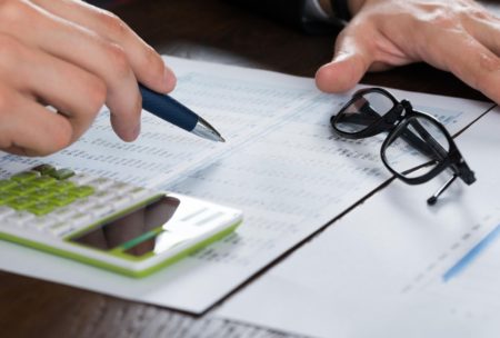 a businessman’s hands engaged with a calculator and pen on financial documents, representing a personal finance course setting