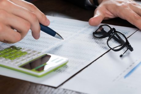 a businessman’s hands engaged with a calculator and pen on financial documents, representing a personal finance course setting