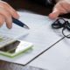 a businessman’s hands engaged with a calculator and pen on financial documents, representing a personal finance course setting