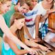 A group of young people having fun playing an old piano, learning easy popular songs to play on piano for beginners