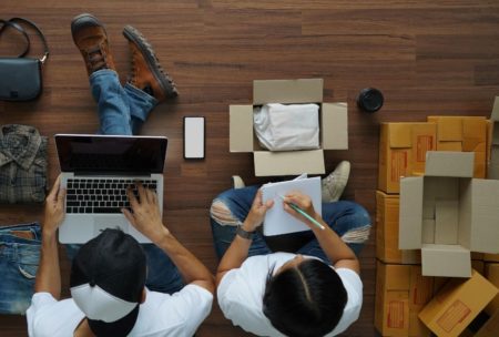 two people on the floor with laptops and boxes, collaborating on an Amazon FBA product launch strategy