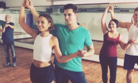 An energetic group session in a dance studio, where people joyfully practice salsa dancing for beginners