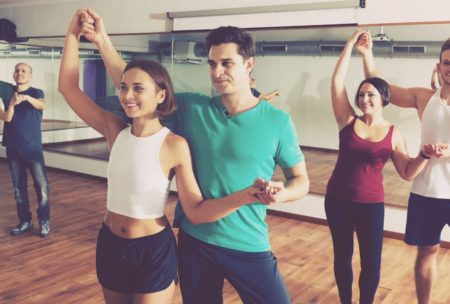 An energetic group session in a dance studio, where people joyfully practice salsa dancing for beginners