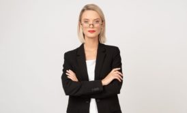 a confident businesswoman in a suit and glasses, symbolizing empowerment and self-confidence lessons
