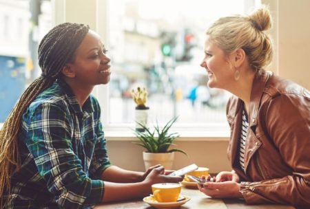 two women sitting at a table, deep in conversation about How To Talk To Anyone