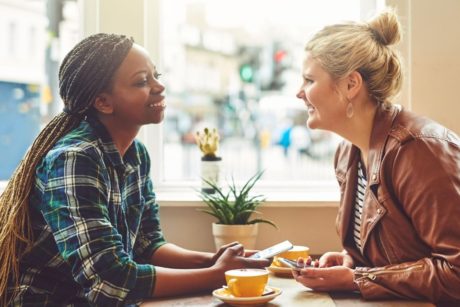 two women sitting at a table, deep in conversation about How To Talk To Anyone