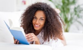 Curly-haired woman deeply engaged in reading Speed Reading Simplified book