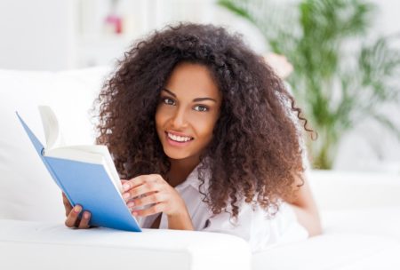 Curly-haired woman deeply engaged in reading Speed Reading Simplified book