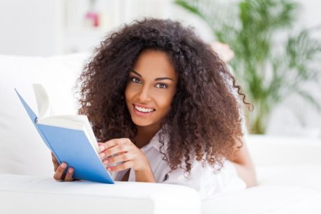 Curly-haired woman deeply engaged in reading Speed Reading Simplified book