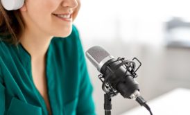 Close-up of a confident woman's face near a microphone, sharing tips on podcasting equipment