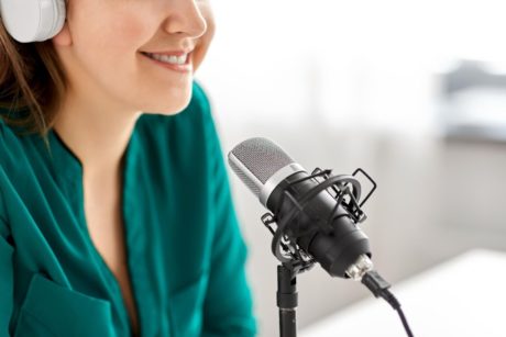 Close-up of a confident woman's face near a microphone, sharing tips on podcasting equipment