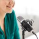 Close-up of a confident woman's face near a microphone, sharing tips on podcasting equipment