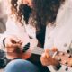 A woman skillfully demonstrates How to Play Ukulele on a cozy couch, showcasing her musical talent and passion