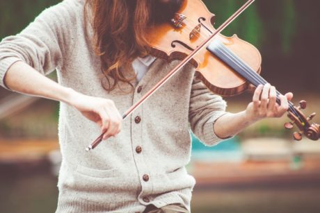 A person learning How to Play the Violin with a bow, creating beautiful music