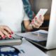woman holding smartphone and tapping on calculator