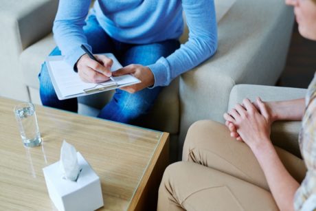 therapist in blue talking to patient