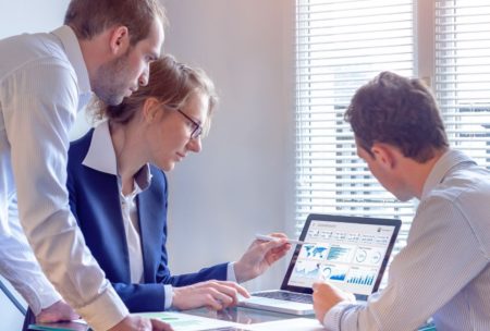 team looking at pivot table on silver laptop