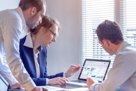 team looking at pivot table on silver laptop