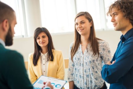 three professionals conversing in an office, focusing on goal setting theory of motivation