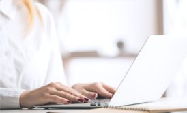 woman typing on white laptop
