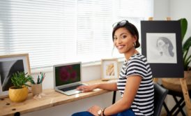 A woman sitting at a desk with a laptop, engaged in selling art online