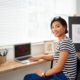 A woman sitting at a desk with a laptop, engaged in selling art online