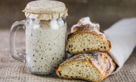 a sourdough bread alongside a jar of sourdough, showcasing the art of sourdough baking class