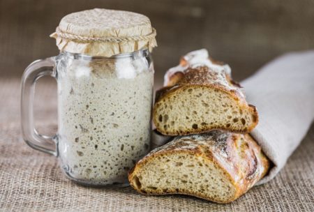 a sourdough bread alongside a jar of sourdough, showcasing the art of sourdough baking class